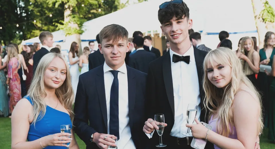 Un gruppo di studenti del Ratcliffe College si trova a un ricevimento all'aperto con alberi sullo sfondo.