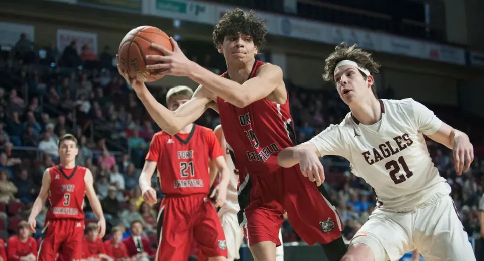 Due giocatrici di basket in maglia rossa e bianca lottano per la palla sul campo da gioco del Guelph Collegiate Vocational Institute.