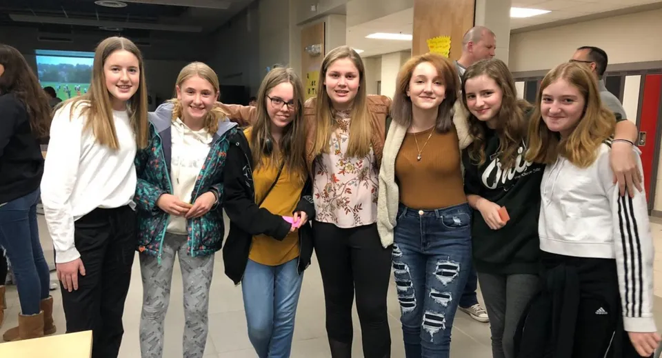 Un gruppo di studentesse sorridenti si trova insieme nel corridoio della Essex District High School.
