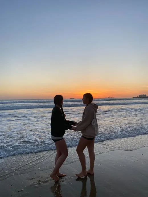 Due ragazze si tengono per mano su una spiaggia spagnola al tramonto