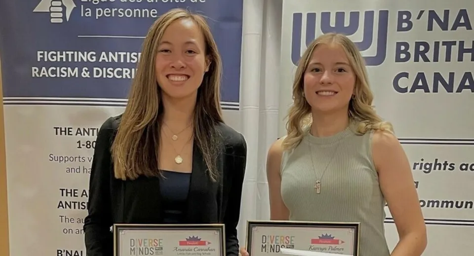 Due donne sorridenti davanti agli striscioni dell'organizzazione antirazzista nel campus della Lillian Osborne High School.