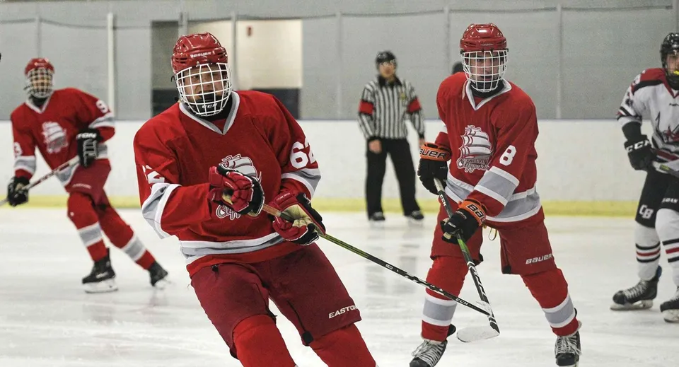 Giocatori di hockey su ghiaccio della École secondaire Kelvin High School con divise rosse sulla pista.