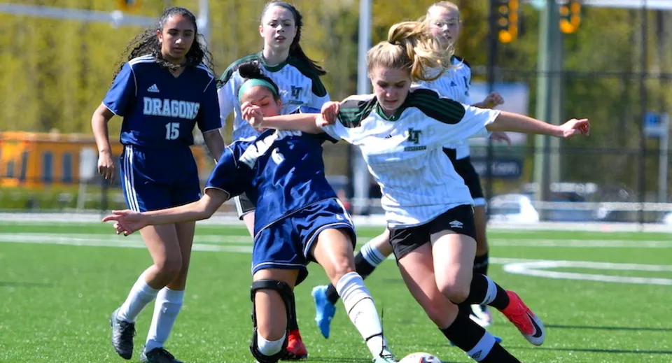 Studentesse della Fleetwood Park Secondary School giocano a calcio e si contendono la palla sul campo da gioco.