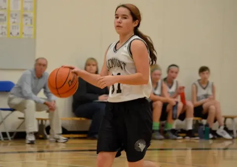 Una studentessa della Valemount Secondary School palleggia con un pallone da basket sul campo da pallacanestro.