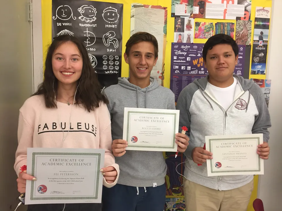Tre studenti della Miami Beach Senior High School tengono in mano dei certificati in un'aula con poster alle pareti.