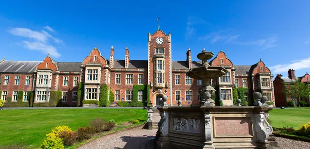 Das historische Gebäude mit Uhrenturm der The Royal School Wolverhampton steht in einem gepflegten Garten mit Springbrunnen.
