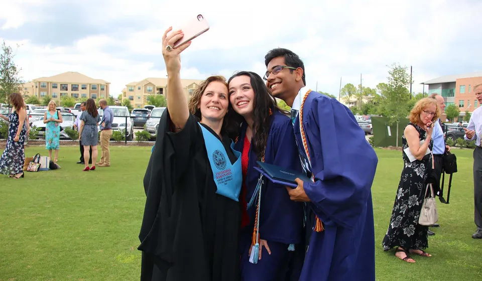 Tre diplomati della The Village School si scattano un selfie nel campus con gli edifici sullo sfondo.