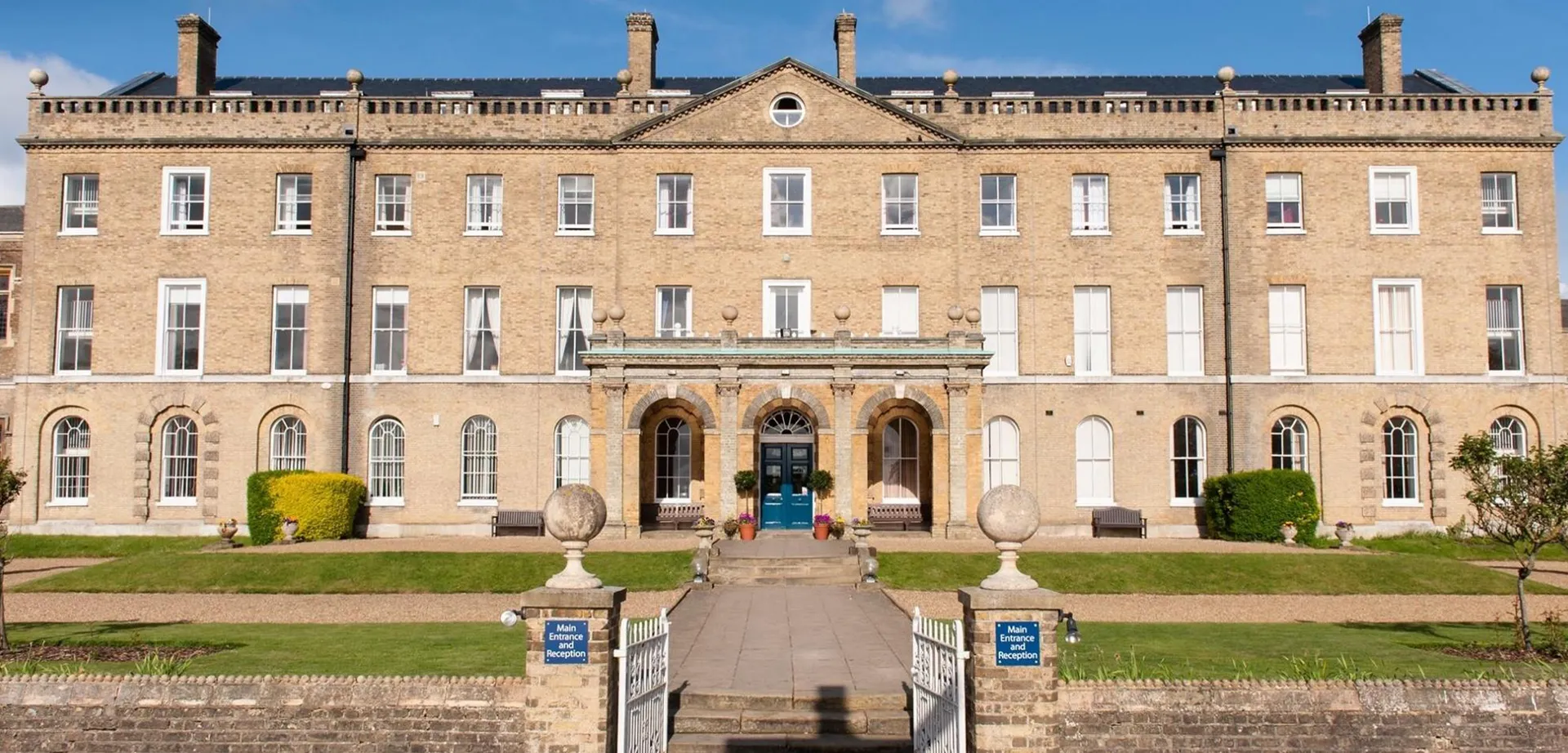 L'imponente edificio principale del St. Edmund’s College è circondato da giardini ben curati con percorsi in pietra e vasi decorativi.