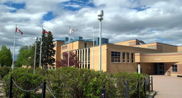 L'edificio in mattoni a più piani della St. Pius X High School si trova in un ambiente verdeggiante con alberi e cespugli.