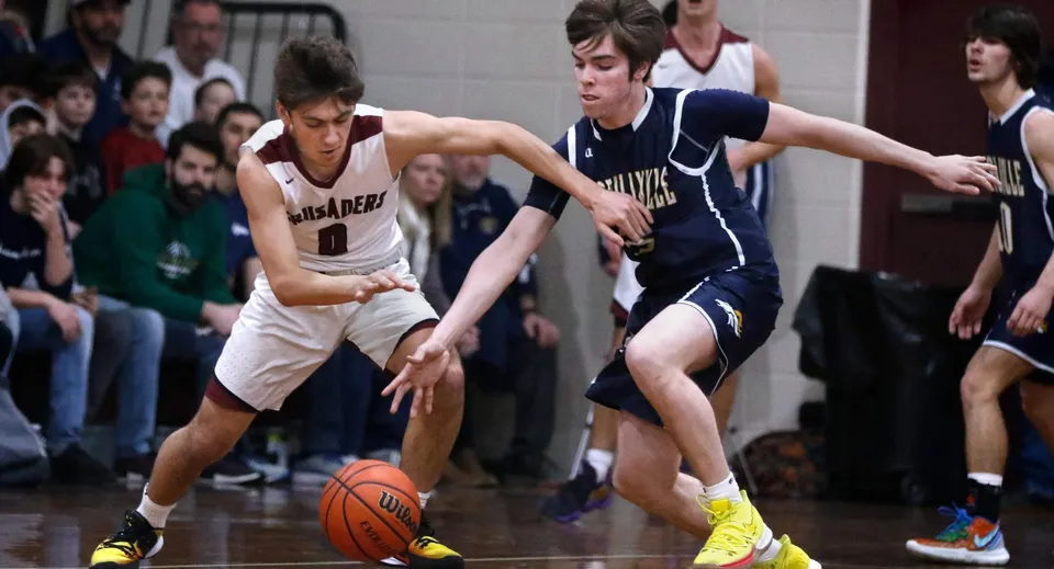 Due giocatori di basket si contendono la palla sul campo della St. Mary’s Diocesan School davanti agli spettatori.