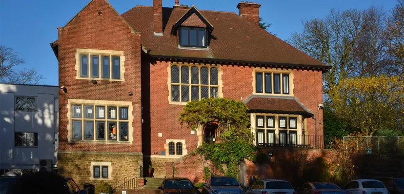 L'edificio in mattoni del Cambridge Tutors College con grandi finestre e auto parcheggiate davanti.