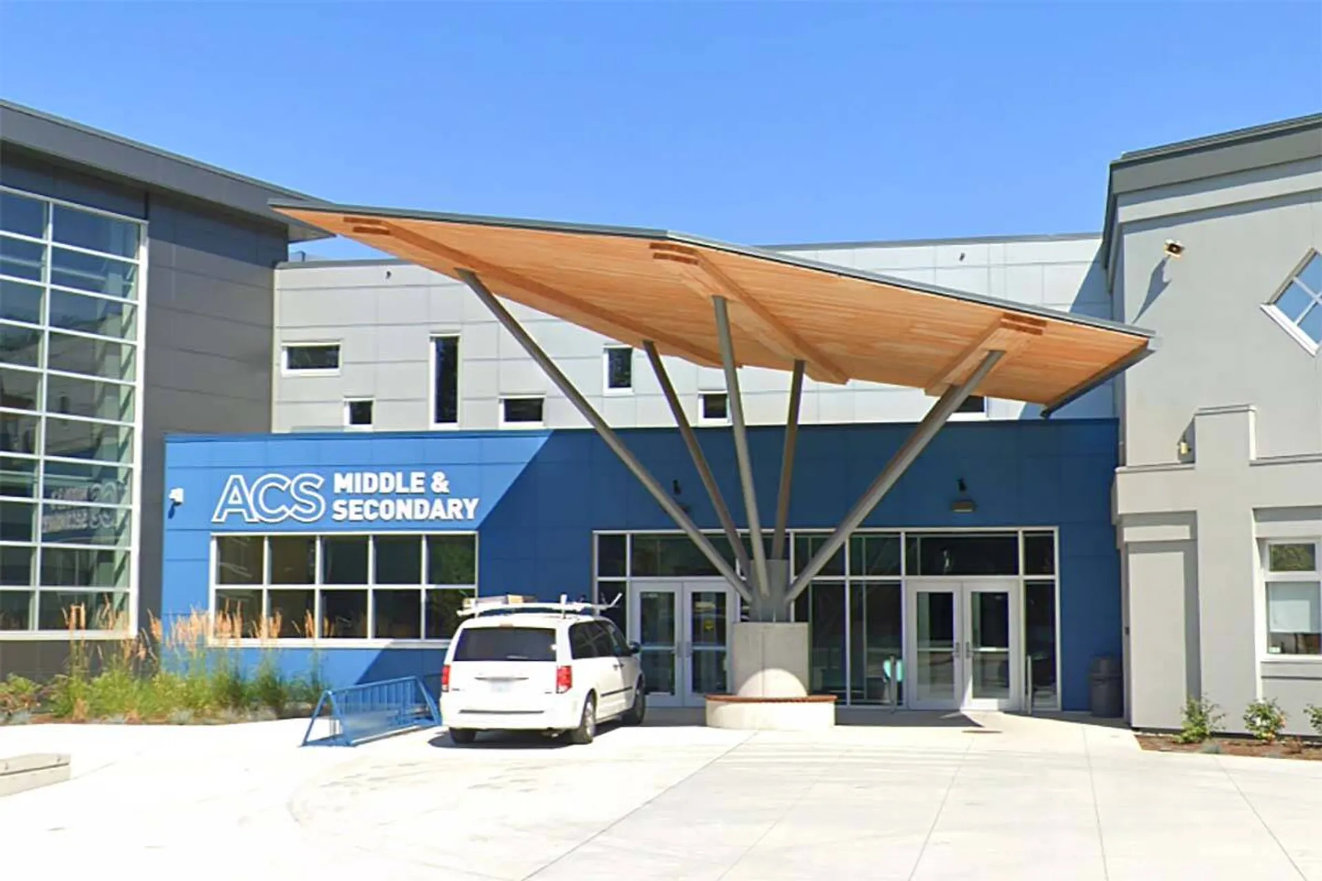 L'edificio moderno a più piani della Abbotsford Christian School con pittura esterna blu e una pensilina in legno all'ingresso.