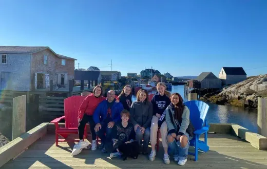 Grupo posando en sillas de madera rojas y azules en un puerto pesquero de casas de madera