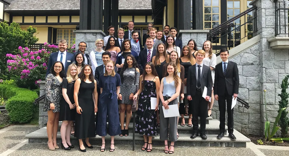 Un gruppo di studentesse e studenti sta insieme sulla scalinata di un edificio storico nel campus della Carson Graham Secondary School.