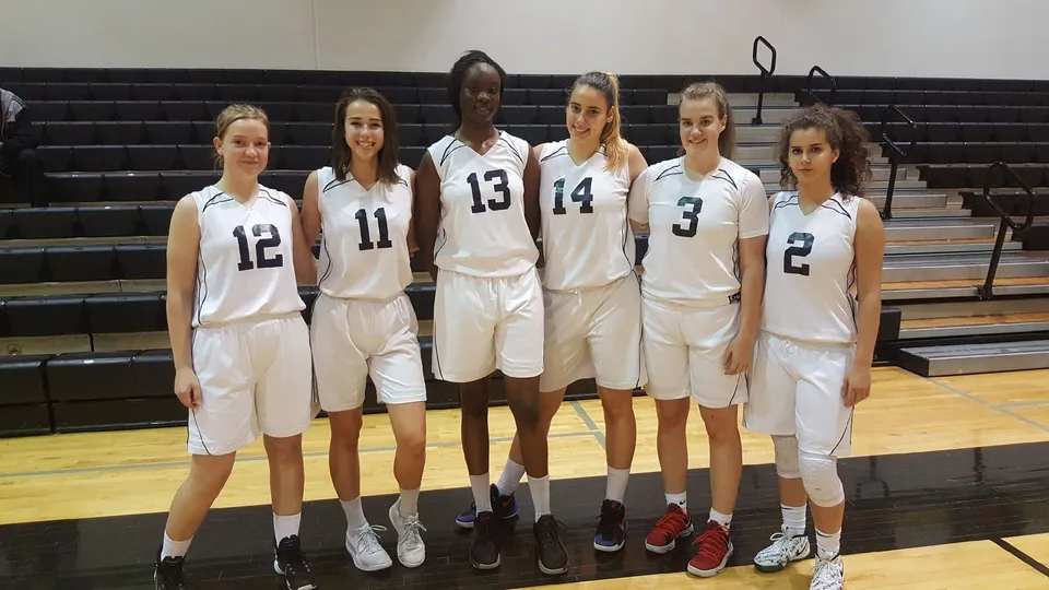 Sei giocatrici di pallacanestro del Bella Vista College Prep posano con divise bianche in una palestra.