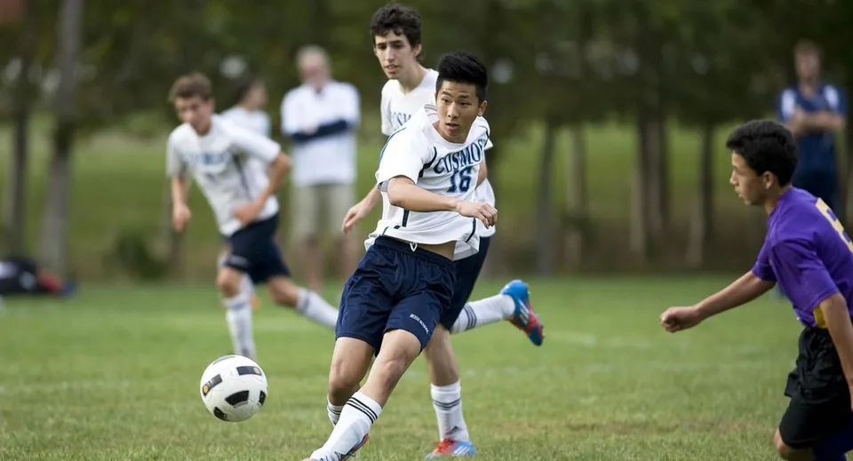 Uno studente della Ross School gioca a calcio su un campo in erba durante una partita.