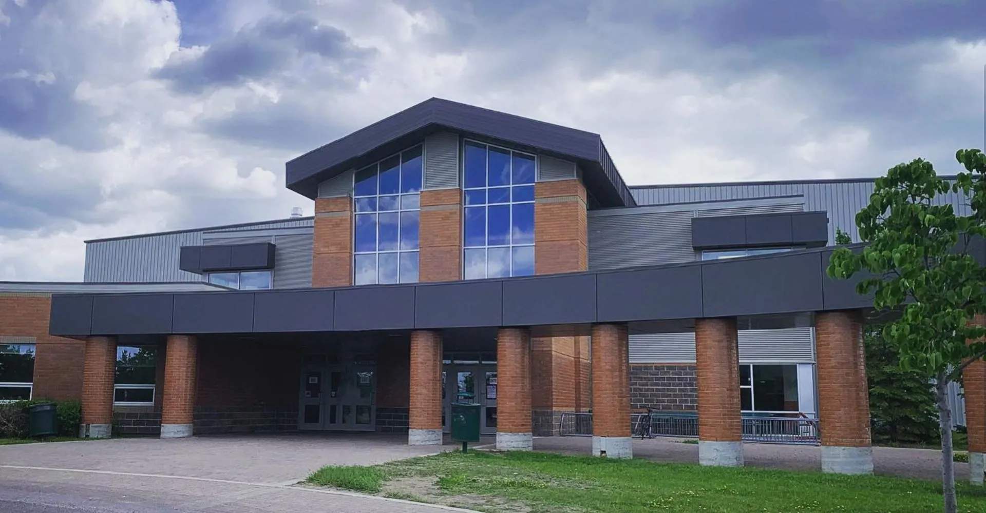L'edificio moderno a più piani del Centennial Collegiate, con una facciata in mattoni e vetro, è circondato da prati e alberi.