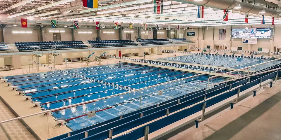 La grande piscina al coperto della SPIRE Academy con diverse corsie, blocchi di partenza e spalti.