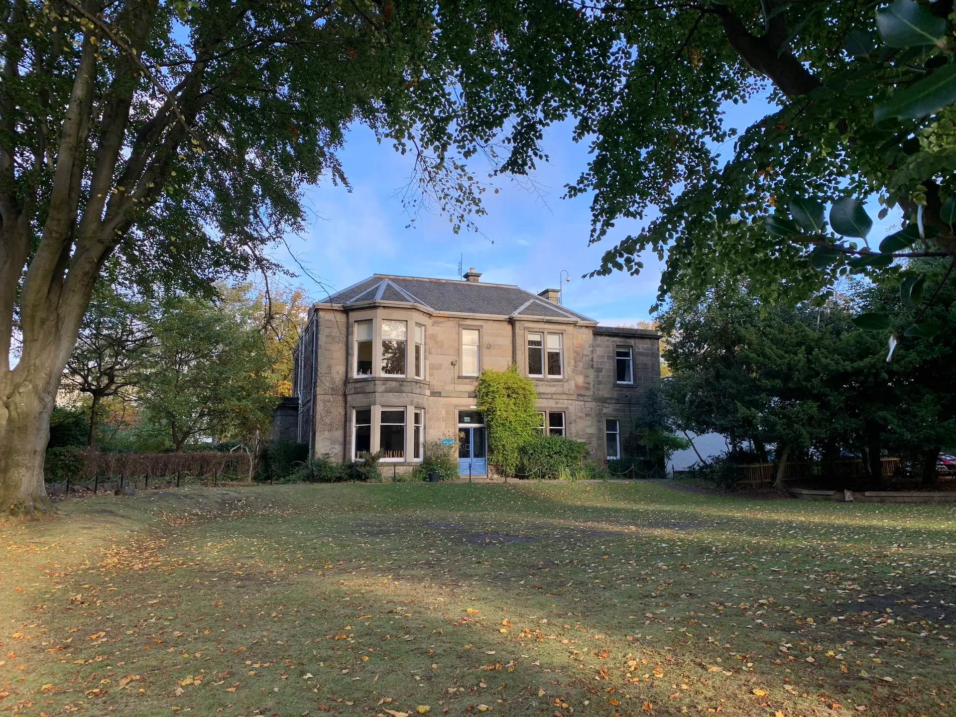 L'edificio in mattoni della Edinburgh Steiner School si trova circondato da alberi autunnali e foglie nel campus della scuola.