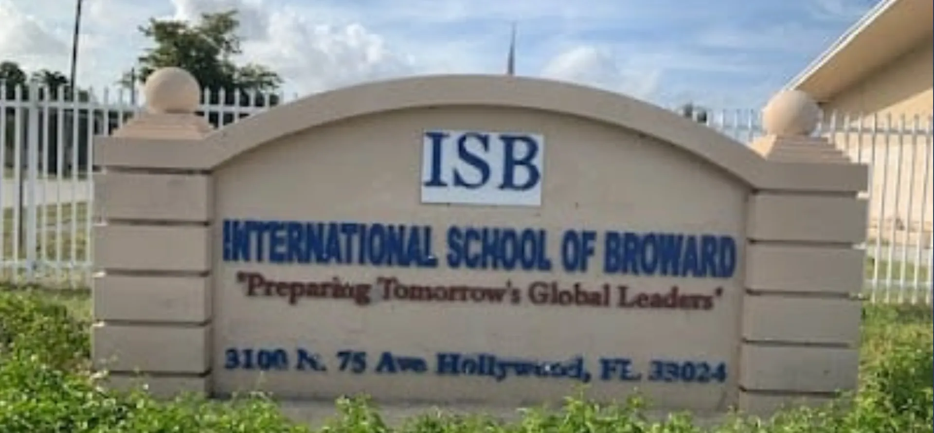 L'insegna della International School of Broward con cielo blu e vegetazione sullo sfondo.