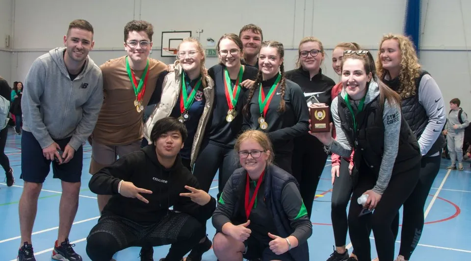 Un gruppo di studenti con medaglie posa in un impianto sportivo della Palmerstown Community School.