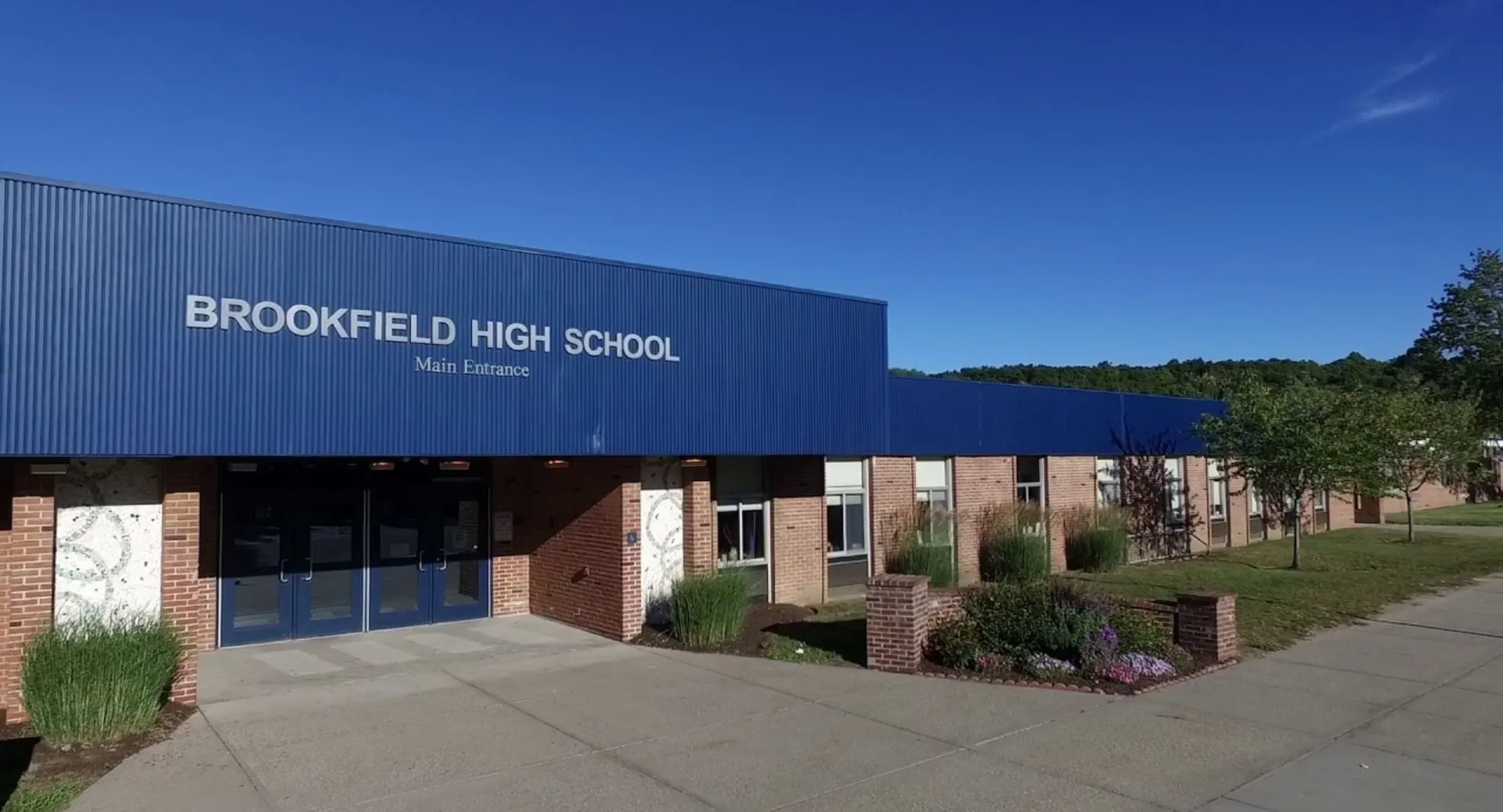 L'ampio edificio blu della Brookfield High School è circondato da un marciapiede pavimentato e da un paesaggio ben curato.
