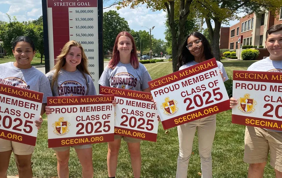 Studenti della Scecina Memorial High School mostrano con orgoglio all'aperto i loro cartelli della Class of 2025.