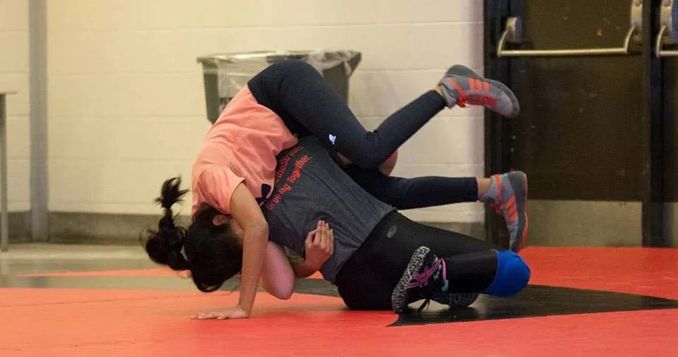 Una studentessa dell'Emery Collegiate Institute fa una verticale su un tappetino rosso in palestra.