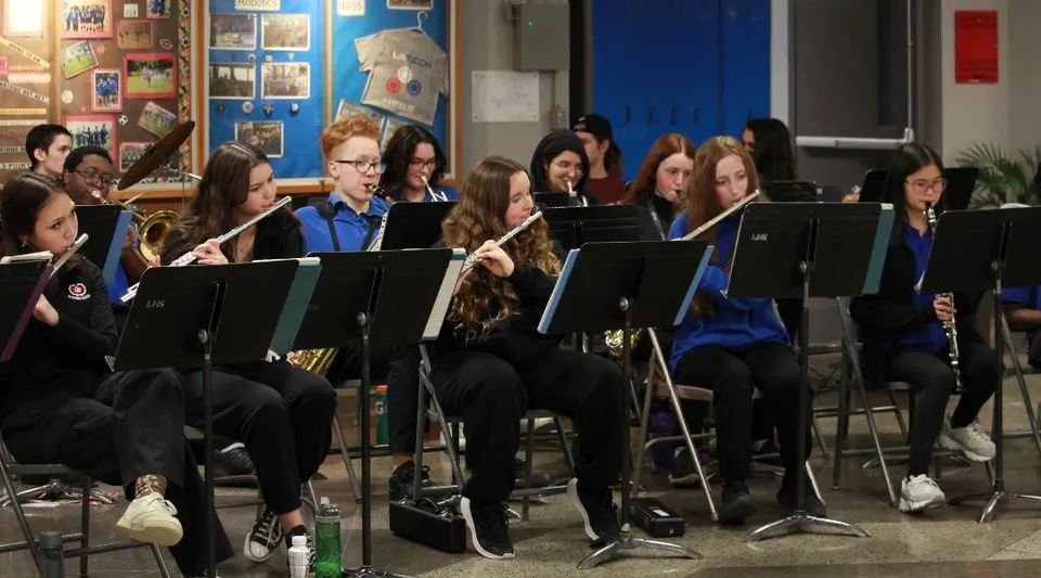 Studenti della Lakeside Academy suonano insieme strumenti musicali in un'aula con vivaci opere d'arte alle pareti.