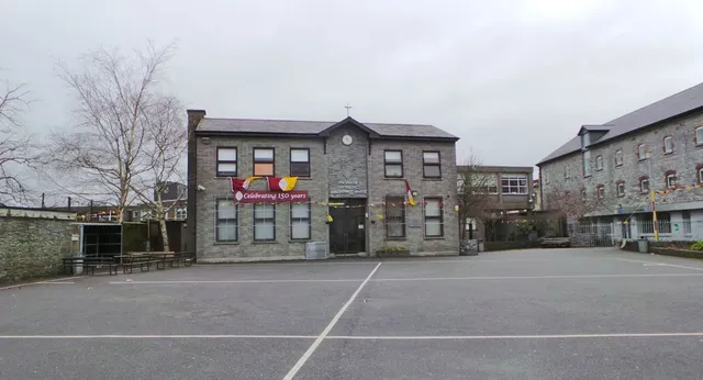 L'edificio principale in pietra della Christian Brothers School Kilkenny con diverse finestre e un cortile pavimentato in primo piano.