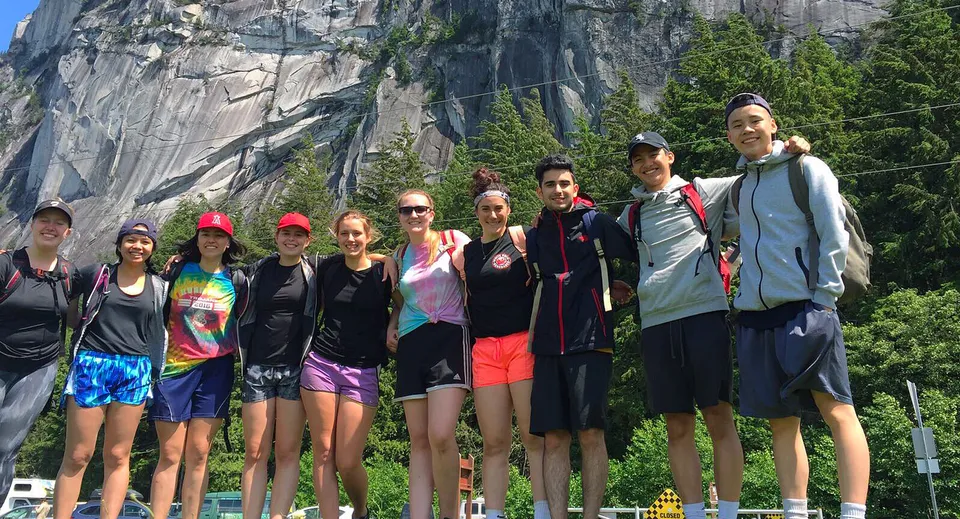 Un gruppo di studenti della Hugh Boyd Secondary School posa davanti a una formazione rocciosa nel bosco.