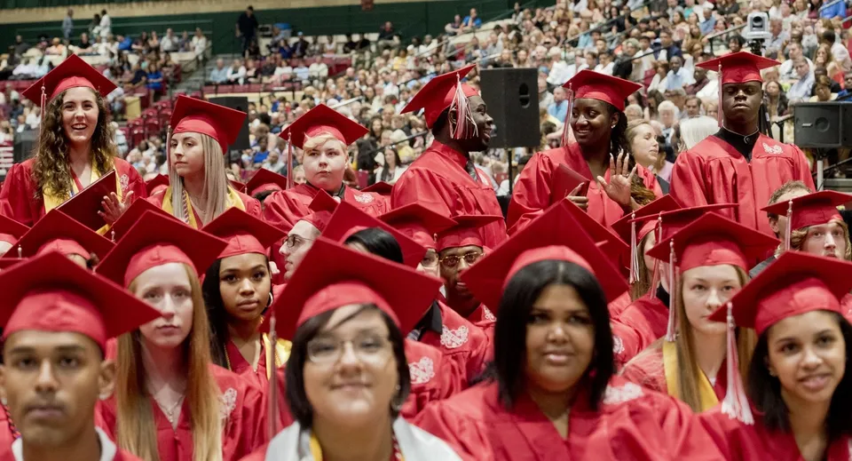 Neodiplomati della Burnie High School insieme in toga rossa durante una cerimonia di diploma.