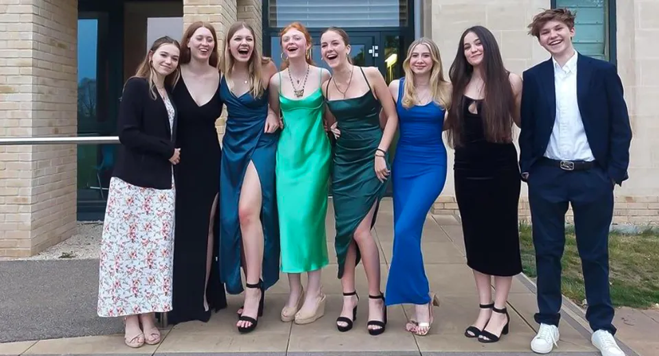 Un gruppo di studenti della St Edward's School Oxford sta in abito formale davanti a un edificio moderno e posa per una foto.