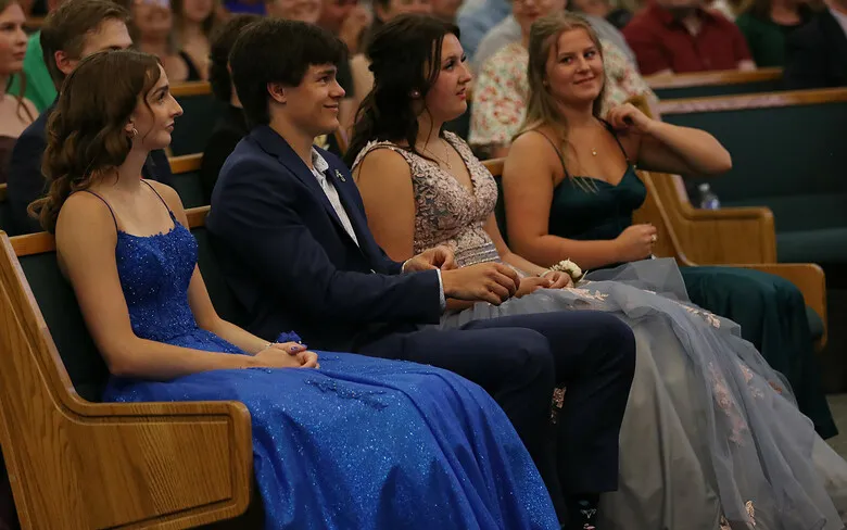 Un grupo de personas vestidas formalmente está sentado en un teatro durante un evento de Immanuel Christian Secondary School.
