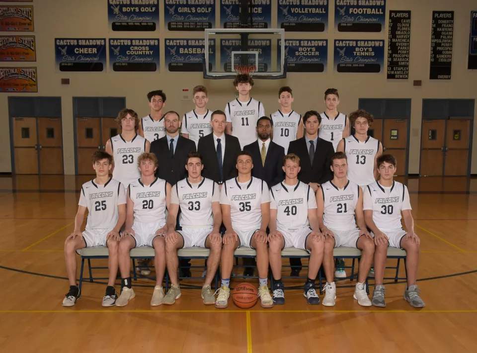 La squadra di basket della Cactus Shadows High School posa insieme agli allenatori nella palestra.