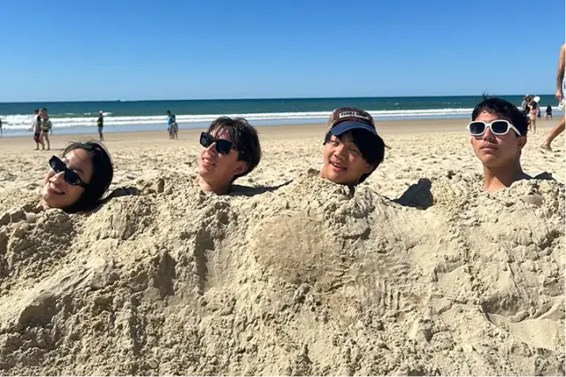 Tre ragazze sorridenti su una spiaggia australiana al tramonto