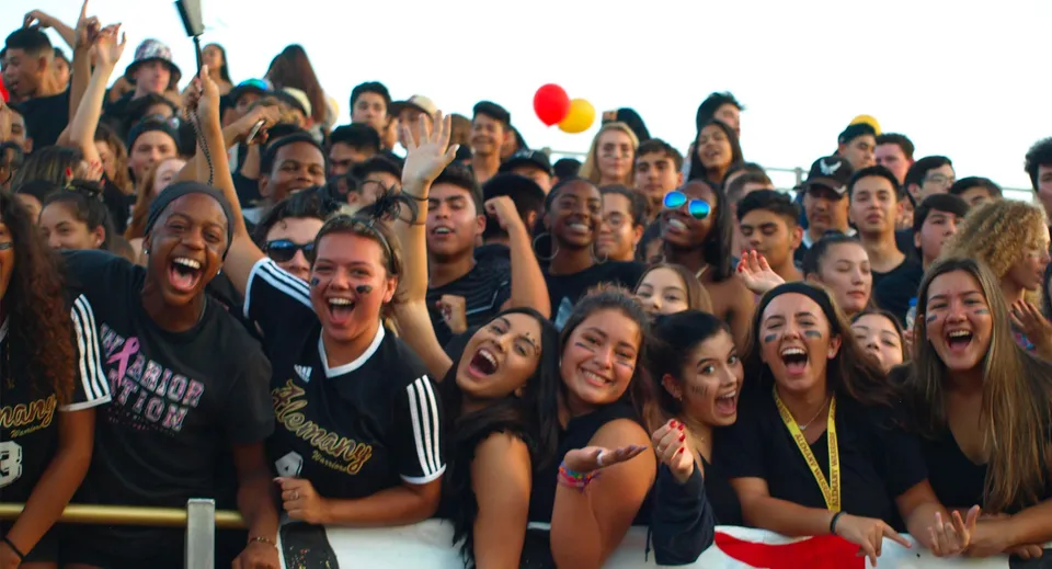 Un grande gruppo di studenti della Bishop Alemany High School si riunisce festeggiando durante un evento.