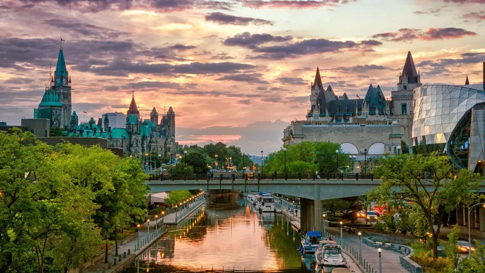 Un canale romantico circondato da alberi passa accanto a un edificio simile a un castello all'interno del campus della École secondaire publique Louis-Riel.