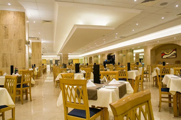 Sala ristorante dell'hotel con tavoli apparecchiati con tovaglie bianche e sedie in legno chiaro