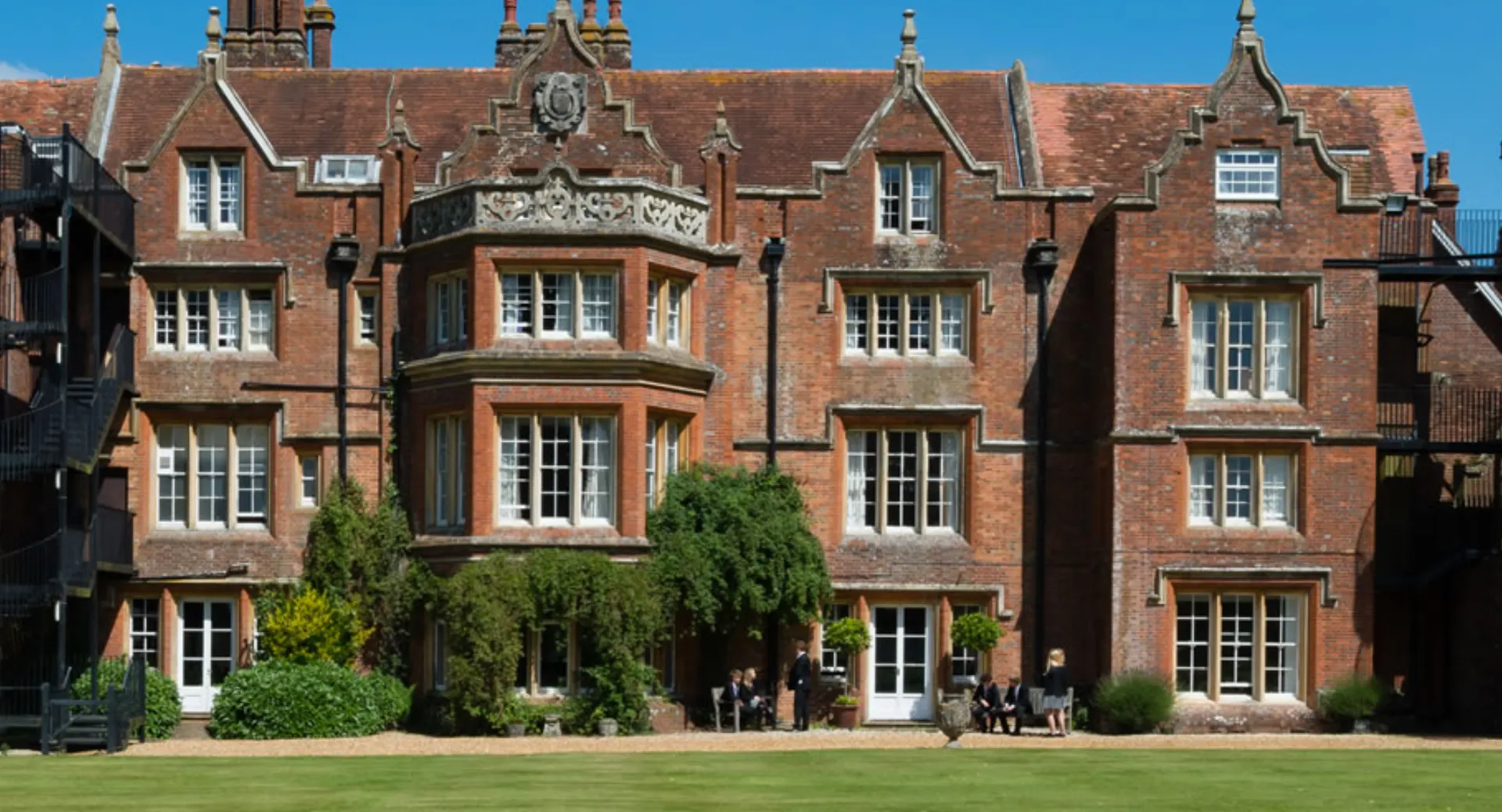 L'edificio storico in mattoni decorati nel campus della Embley School è circondato da un cortile verde in cui passeggiano gli studenti.