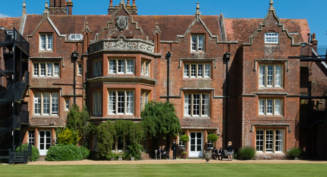 L'edificio storico in mattoni decorati nel campus della Embley School è circondato da un cortile verde in cui passeggiano gli studenti.