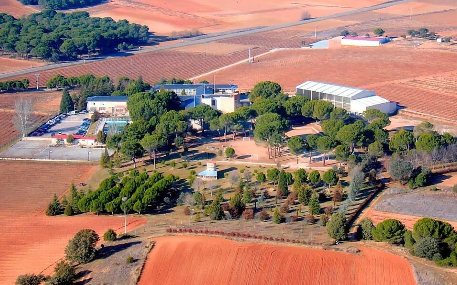 Veduta aerea del paesaggio rurale con campi e bosco sullo sfondo vicino al Colegio San Gabriel.