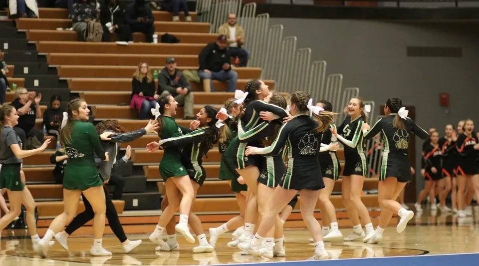 Un gruppo di cheerleader della Comstock Park High School si esibisce sul campo da basket davanti al pubblico.