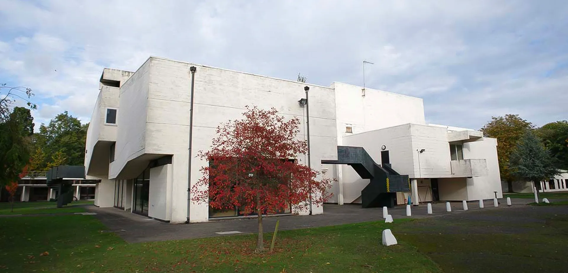 L'edificio moderno e bianco della International School of Creative Arts con una scala esterna scura e un piccolo albero rosso.