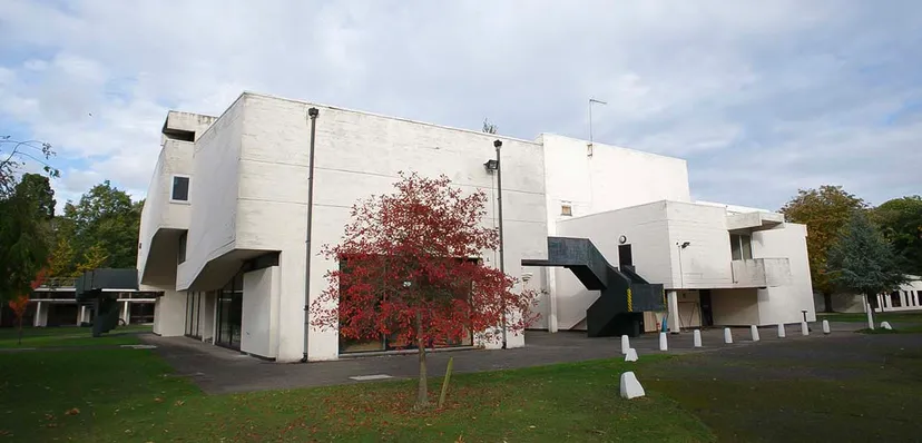 L'edificio moderno e bianco della International School of Creative Arts con una scala esterna scura e un piccolo albero rosso.