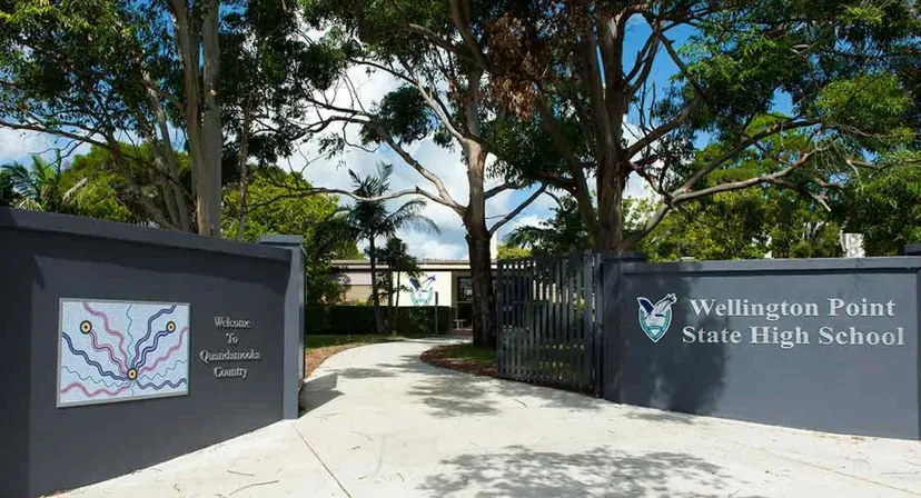 L'ingresso della Wellington Point State High School con l'insegna dell'edificio scolastico, circondato da alberi e piante.