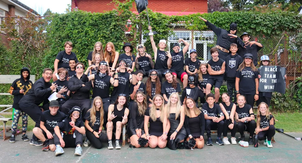 Un grande gruppo di studenti della St. Patrick’s High School di Québec City posa davanti a un edificio in mattoni con aree verdi.