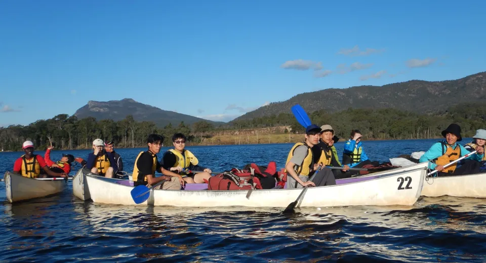 Studenti del Calamvale Community College fanno un'escursione in barca su un lago di montagna sotto un cielo blu.