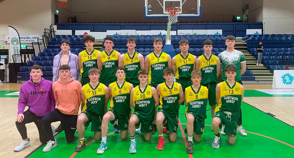 Un gruppo di studentesse e studenti della Gortnor Abbey posa insieme sul campo da basket con il canestro sullo sfondo.