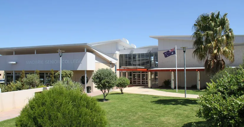 L'edificio moderno e bianco con palme e un prato ben curato nel campus del Mindarie Senior College sotto un cielo azzurro e limpido.